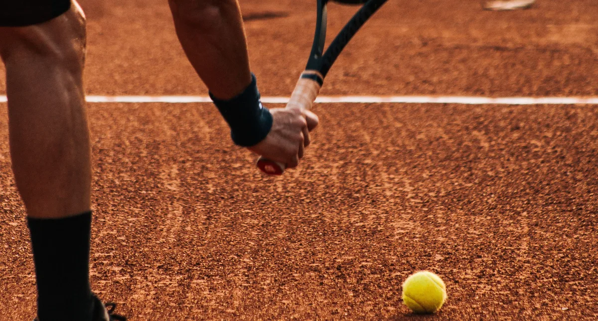 Tennis player on a clay court, racket in hand, about to serve
